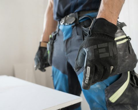 a man wearing a pair of black and blue work gloves
