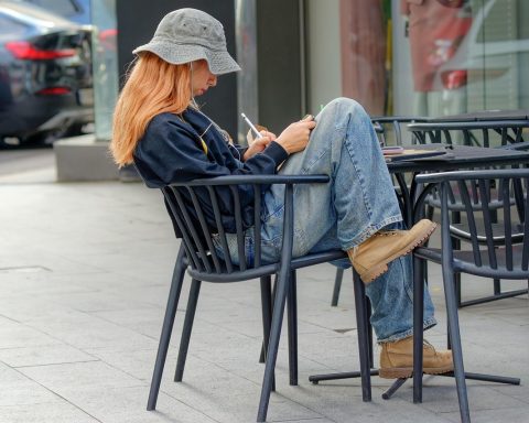 Persoon zit op een terras met een notitieboek en denkt na over een carrièreswitch in de zomer