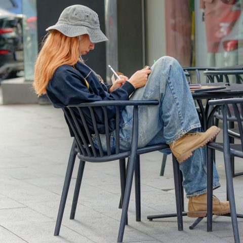 Persoon zit op een terras met een notitieboek en denkt na over een carrièreswitch in de zomer