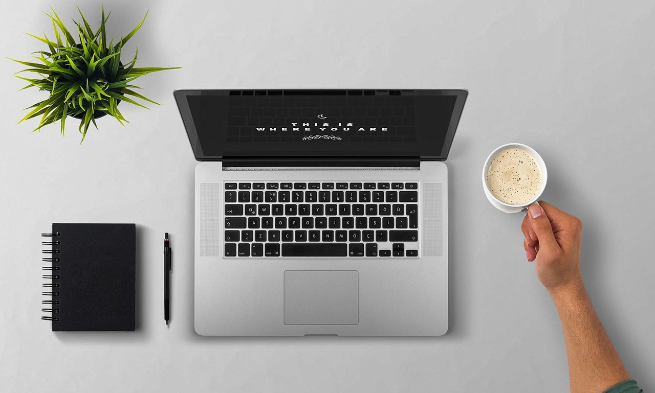 Persoon die aan een laptop werkt in een koffiebar als freelancer