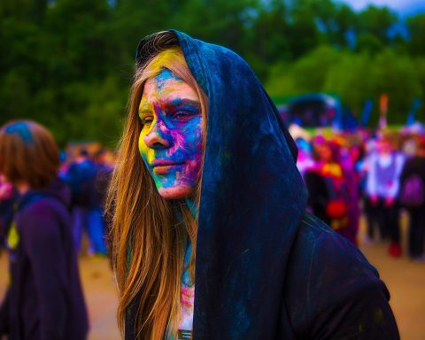 Persoon met kleurrijke make-up in de regen op een festival
