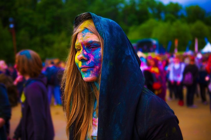 Persoon met kleurrijke make-up in de regen op een festival