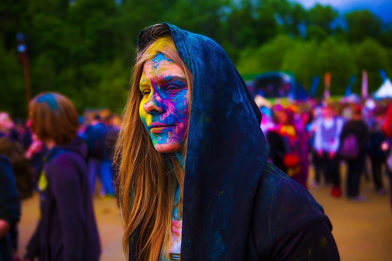 Persoon met kleurrijke make-up in de regen op een festival