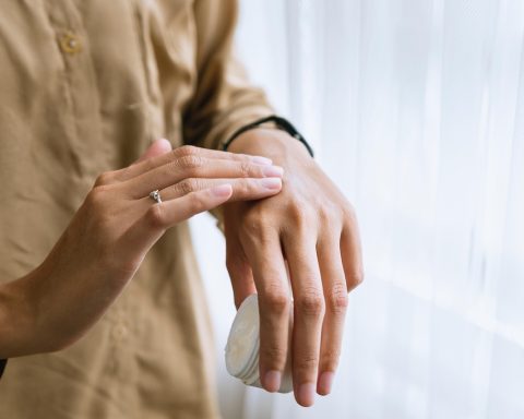 Persoon die 's ochtends rustig gezichtscrème aanbrengt als onderdeel van een verzorgingsritueel