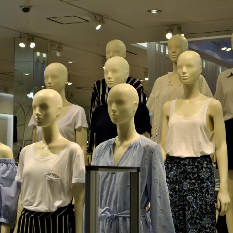 Vrouw past een gekleurde blouse in een paskamer en bekijkt zichzelf in de spiegel