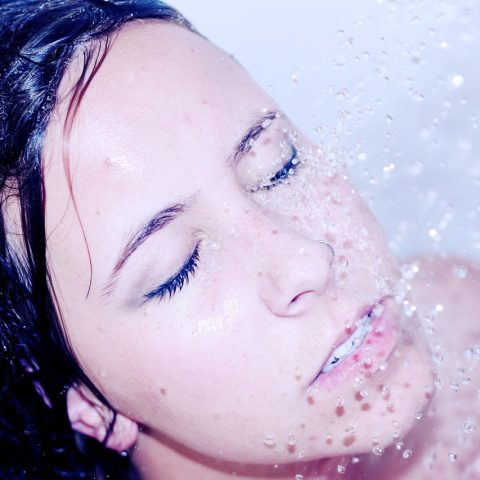 Vrouw die haar gezicht afspoelt onder de douche na het zwemmen