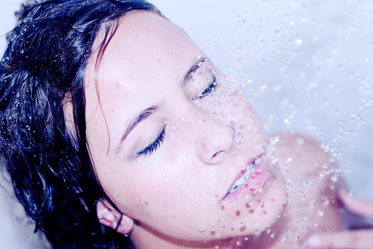 Vrouw die haar gezicht afspoelt onder de douche na het zwemmen