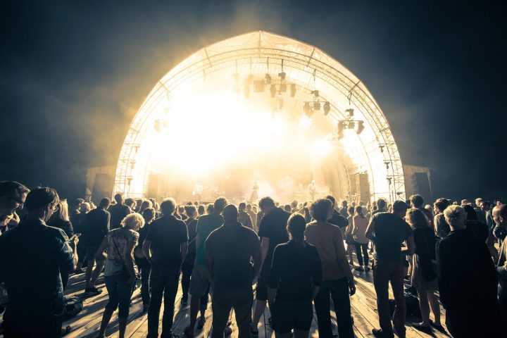 Publiek bij een zomers muziekfestival in Nederland met gekleurde kleding en podiumverlichting