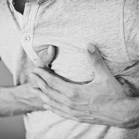 Persoon zit rustig met handen op de borst en oefent een lichaamsscan