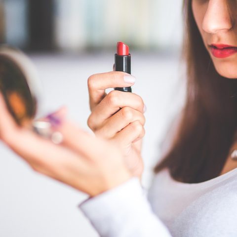 Vrouw die haar haarwortels bekijkt in de spiegel om te beoordelen of haar haar gewassen moet worden
