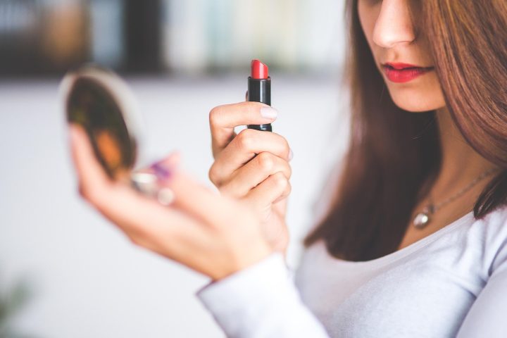 Vrouw die haar haarwortels bekijkt in de spiegel om te beoordelen of haar haar gewassen moet worden