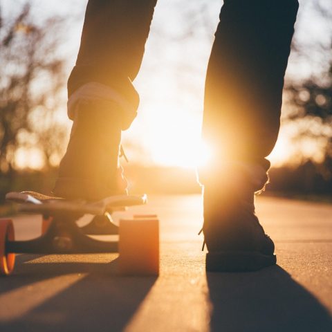 Een tiener leert skateboarden op een lege parkeerplaats met beschermingsuitrusting