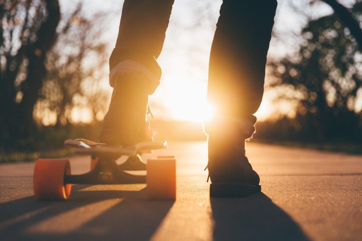 Een tiener leert skateboarden op een lege parkeerplaats met beschermingsuitrusting