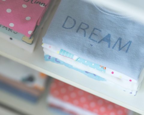 Roze en blauwe babykleding naast elkaar op een rek in een winkel