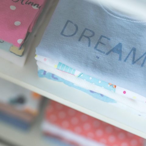 Roze en blauwe babykleding naast elkaar op een rek in een winkel