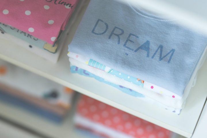 Roze en blauwe babykleding naast elkaar op een rek in een winkel