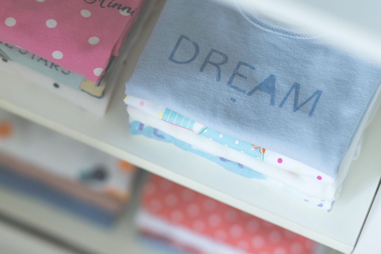 Roze en blauwe babykleding naast elkaar op een rek in een winkel