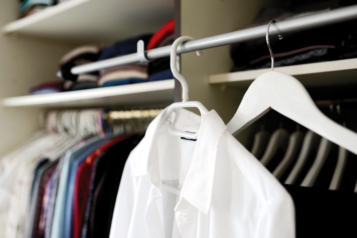 Vrouw die bij een kledingkast vol zwarte kleding staat en een outfit kiest