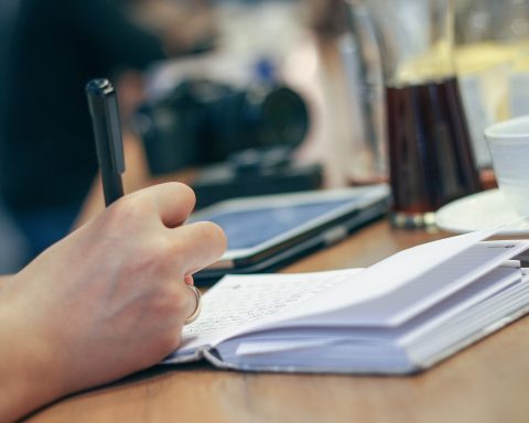 Persoon schrijft in notitieboek aan bureau tijdens zelfonderzoek voor carrièrerichting
