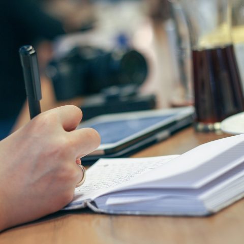 Persoon schrijft in notitieboek aan bureau tijdens zelfonderzoek voor carrièrerichting