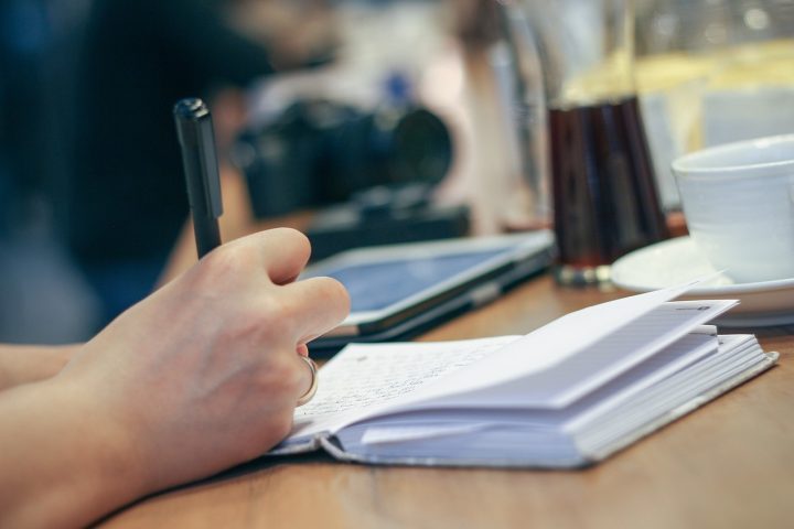 Persoon schrijft in notitieboek aan bureau tijdens zelfonderzoek voor carrièrerichting