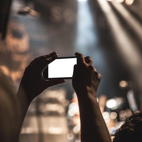 Bovenaanzicht van kleding op een lichte ondergrond tijdens het fotograferen met een smartphone