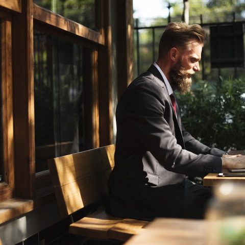 Persoon die op een laptop werkt met een kop koffie naast zich, in een rustige omgeving